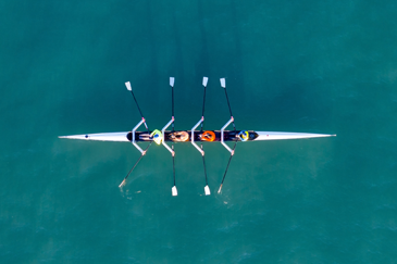 aerial view of a rowing boat with four rowers on calm water